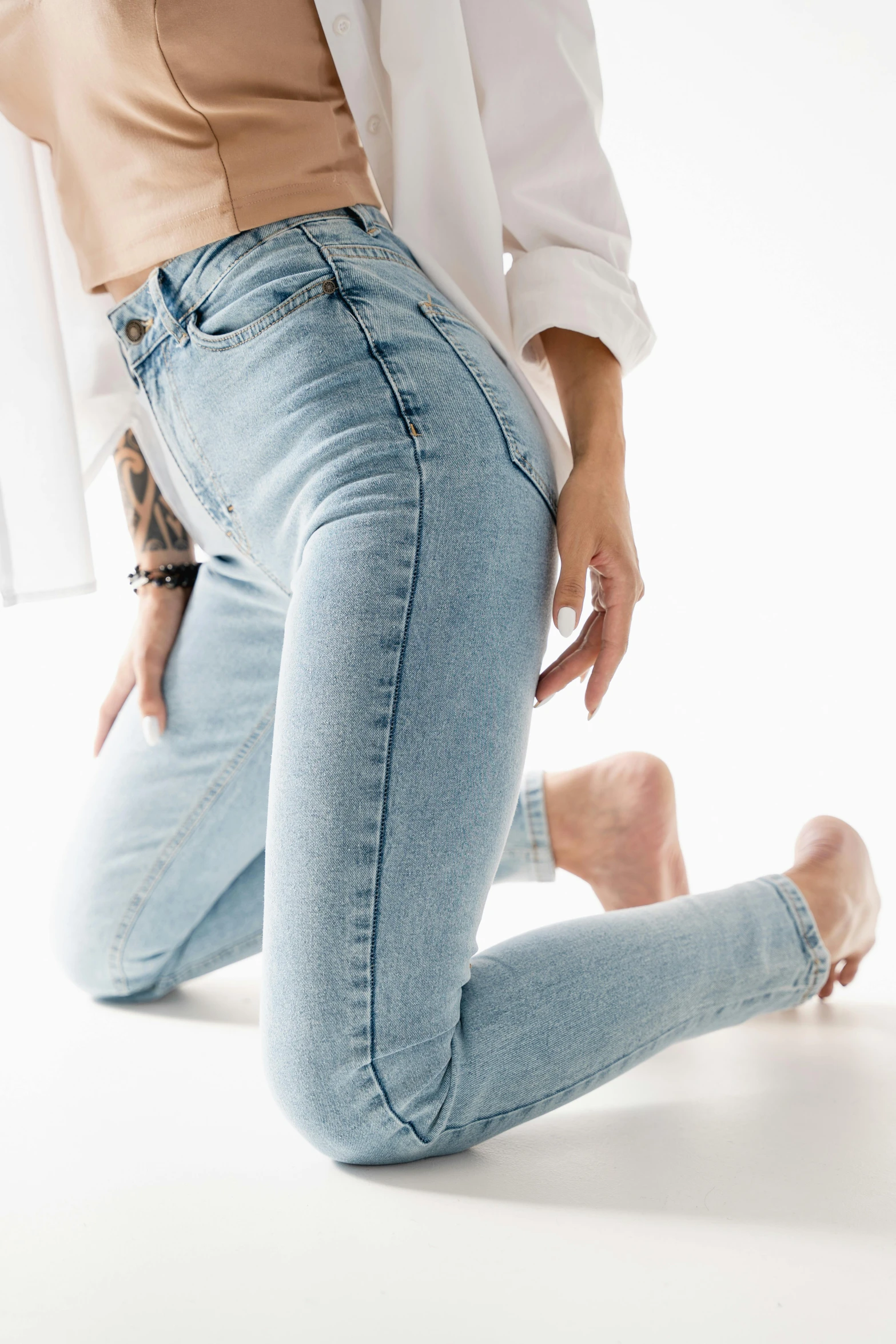 woman with tattoo on leg sitting on the ground in jeans