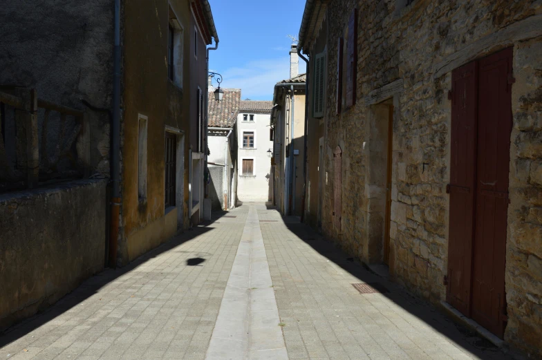 the shadows of buildings cast long and narrow lines in an alley