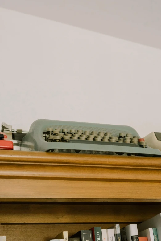 an old fashioned keyboard sits on top of a bookshelf