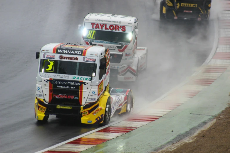 the truck is driving in the race with other cars behind it