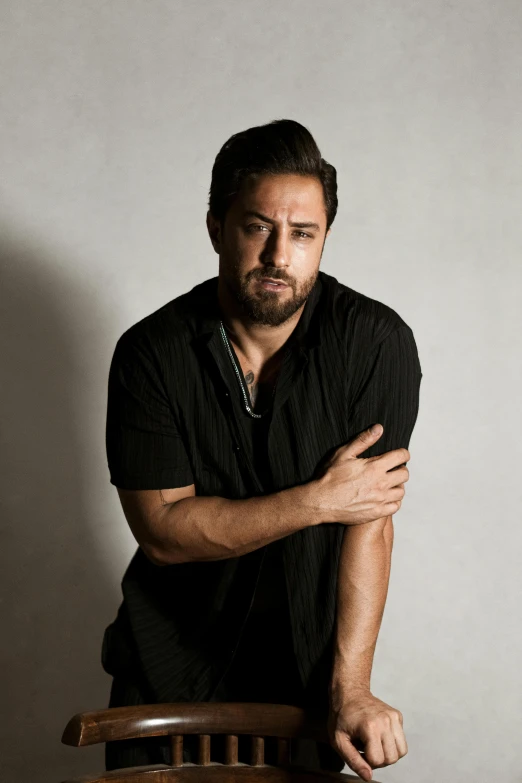 a man sitting at a wooden table with his arms folded over his knees