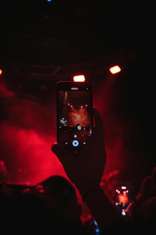 a person holding up a cell phone at a concert