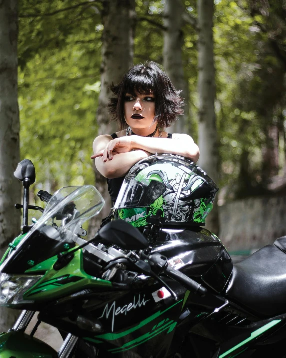 a beautiful young lady wearing a black dress with green accents on her motorcycle