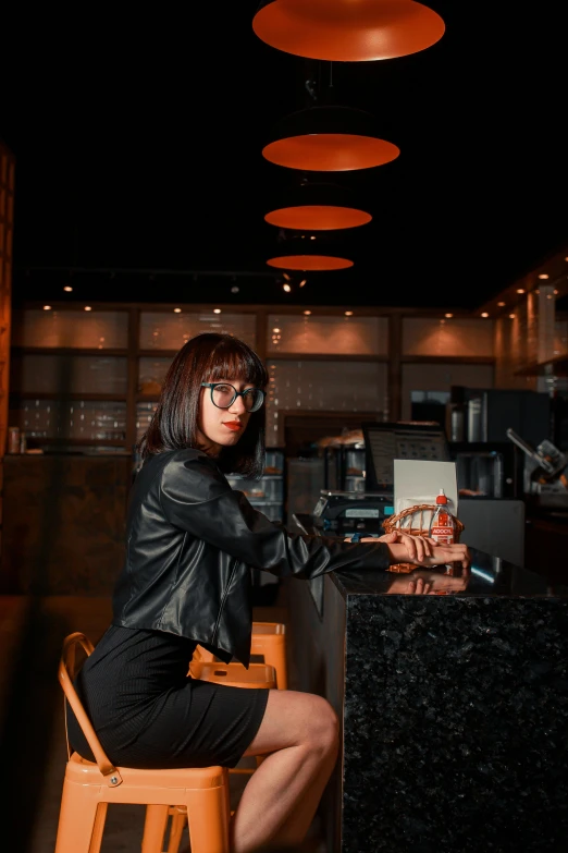 a woman in leather is sitting at the counter