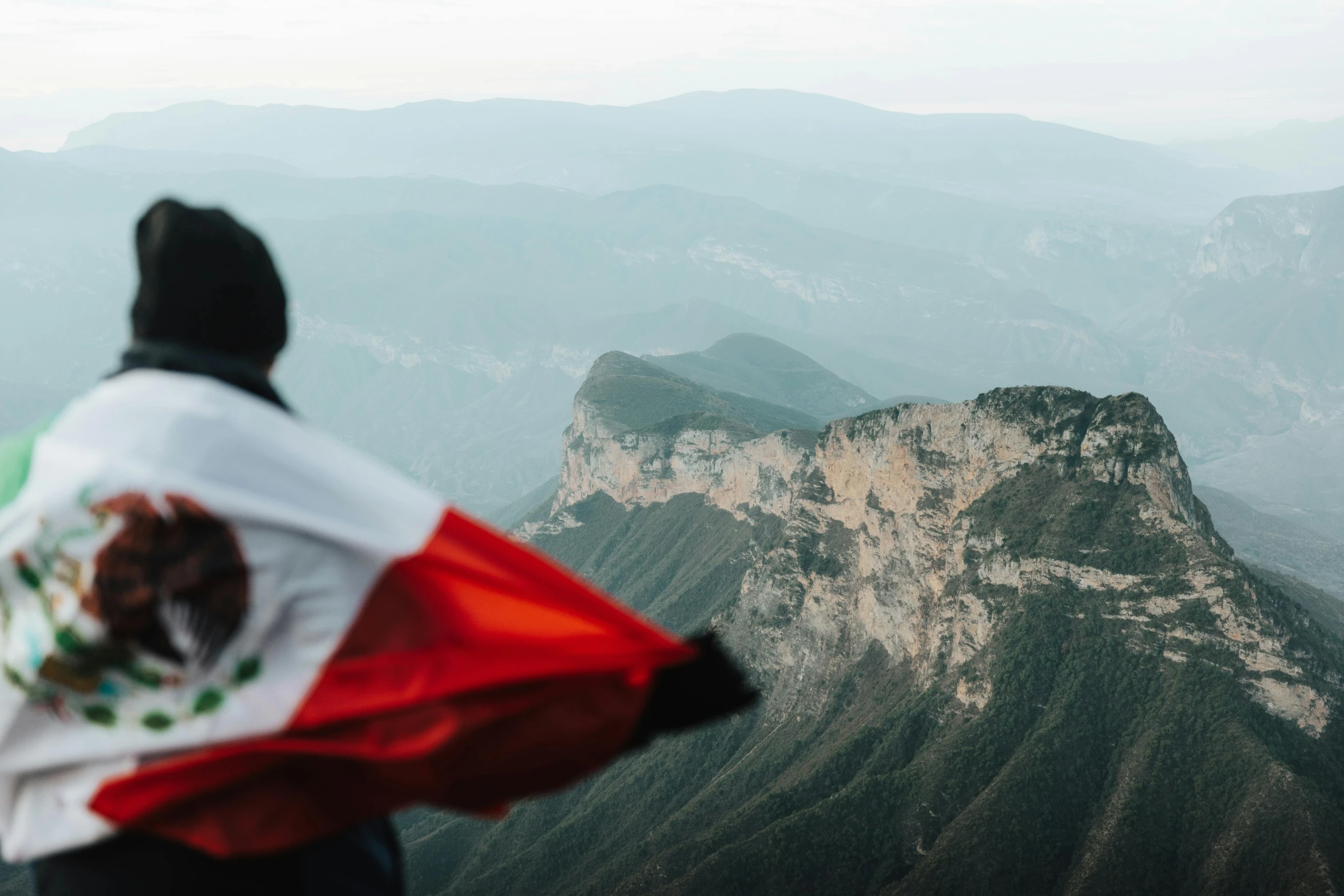 a man is on the top of the mountain with his mexican flag