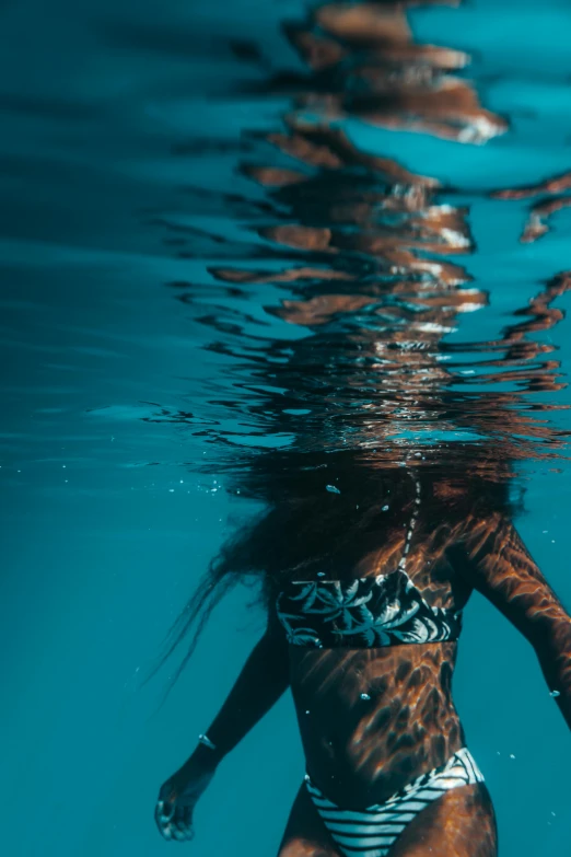 a young woman is under water in a bikini