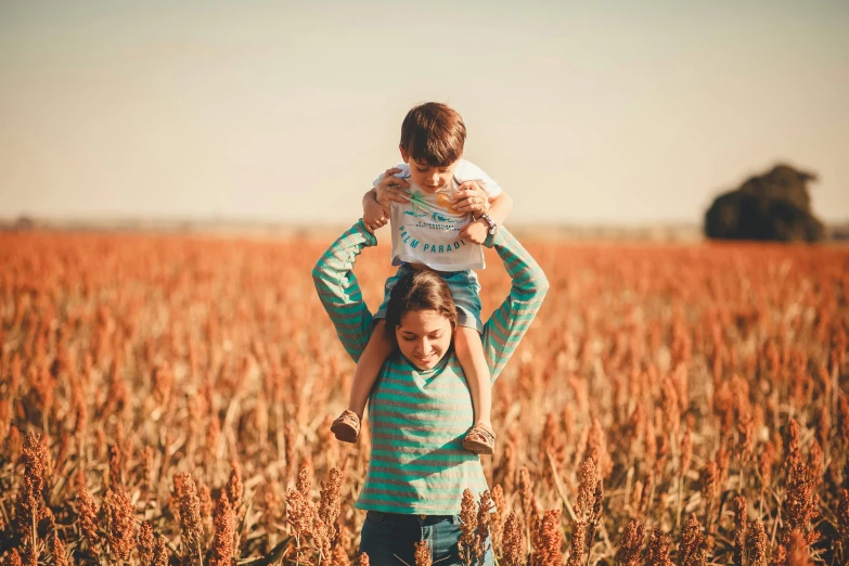 two young children are standing in front of some tall grass