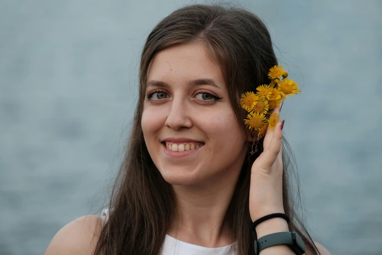 a woman smiles while holding a yellow flower