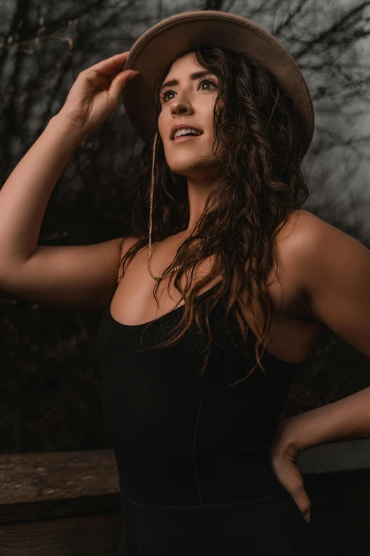 a young woman in black dress and brown hat