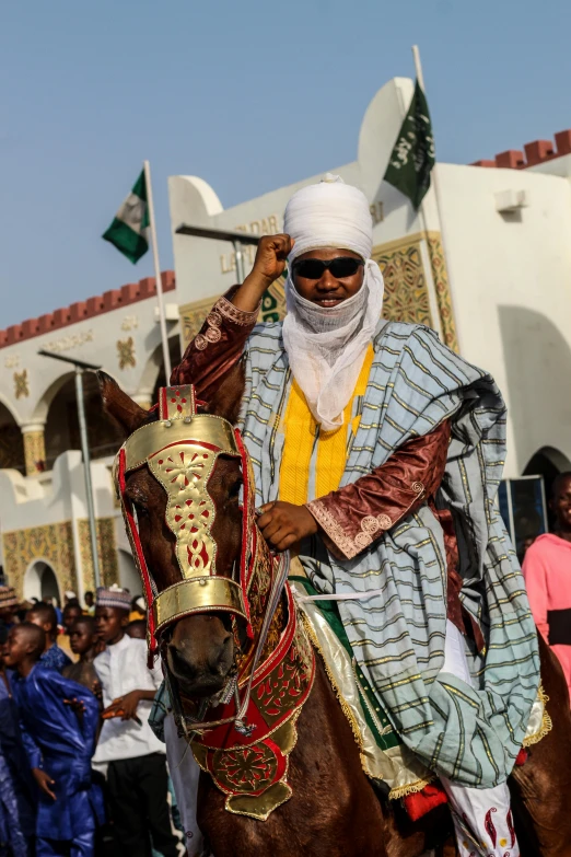 a man in traditional garb rides a horse past a crowd