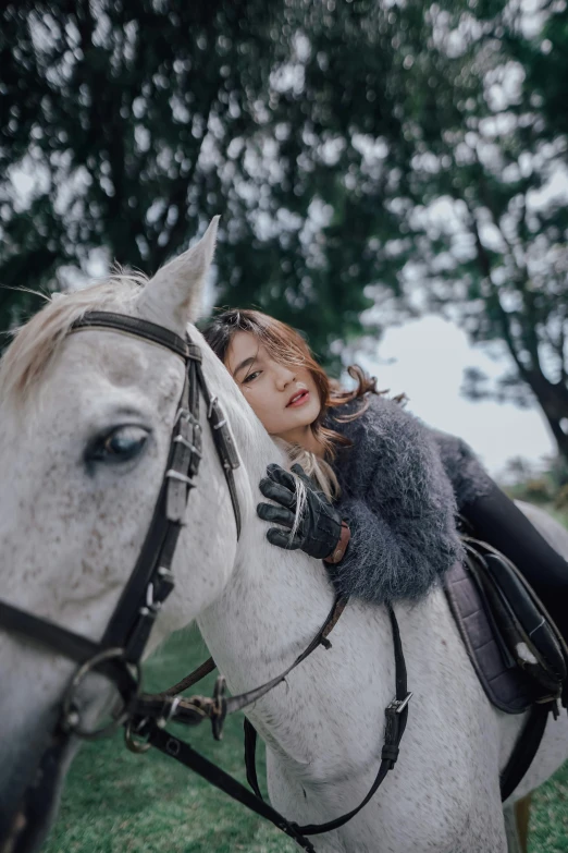 a girl wearing a dress sits on the back of a white horse