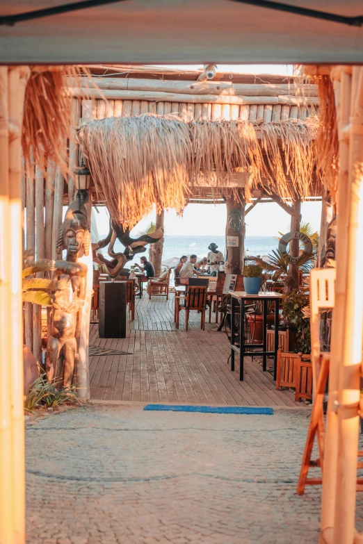 a restaurant with wooden tables, chairs and a thatched roof on a pier