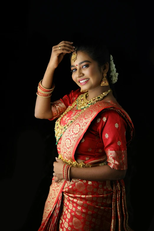 a woman in a red and gold sari smiling for the camera