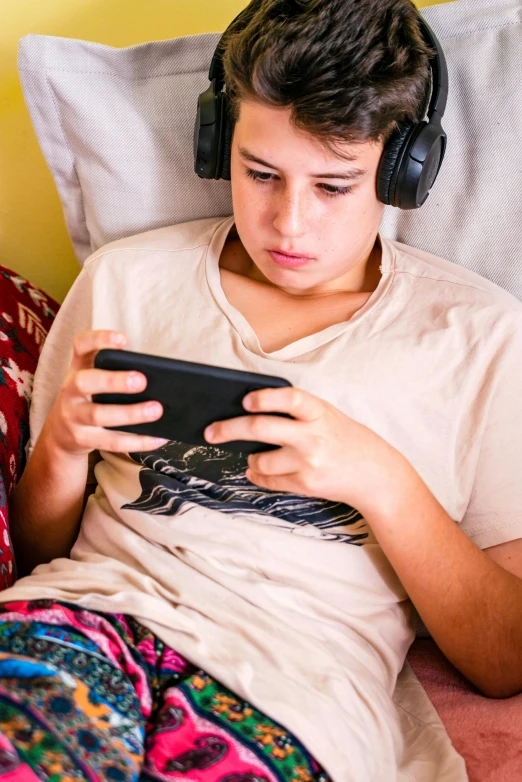 the young person is using the cellphone in the bed