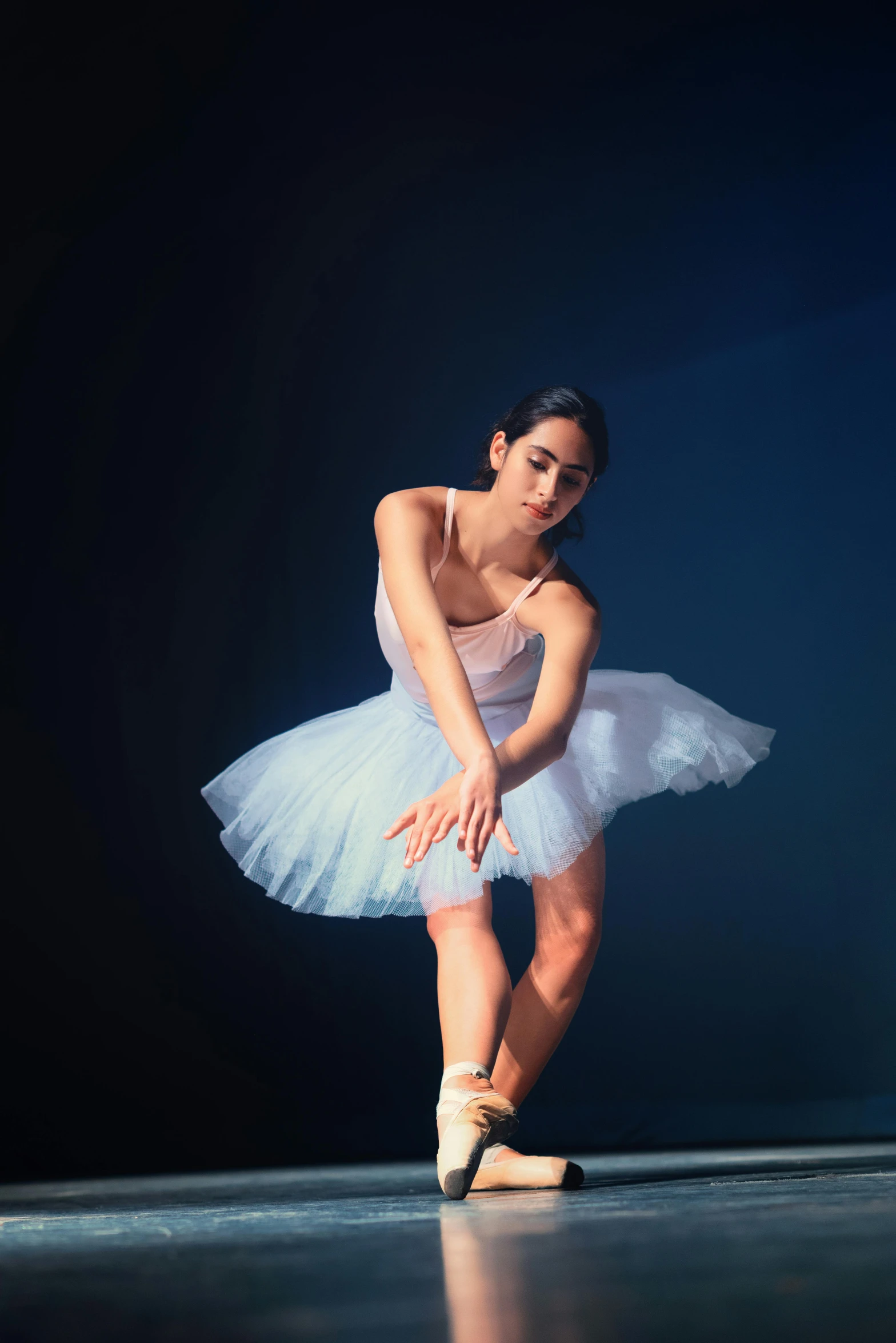 a young ballerina in a white leotrette and ballet shoes