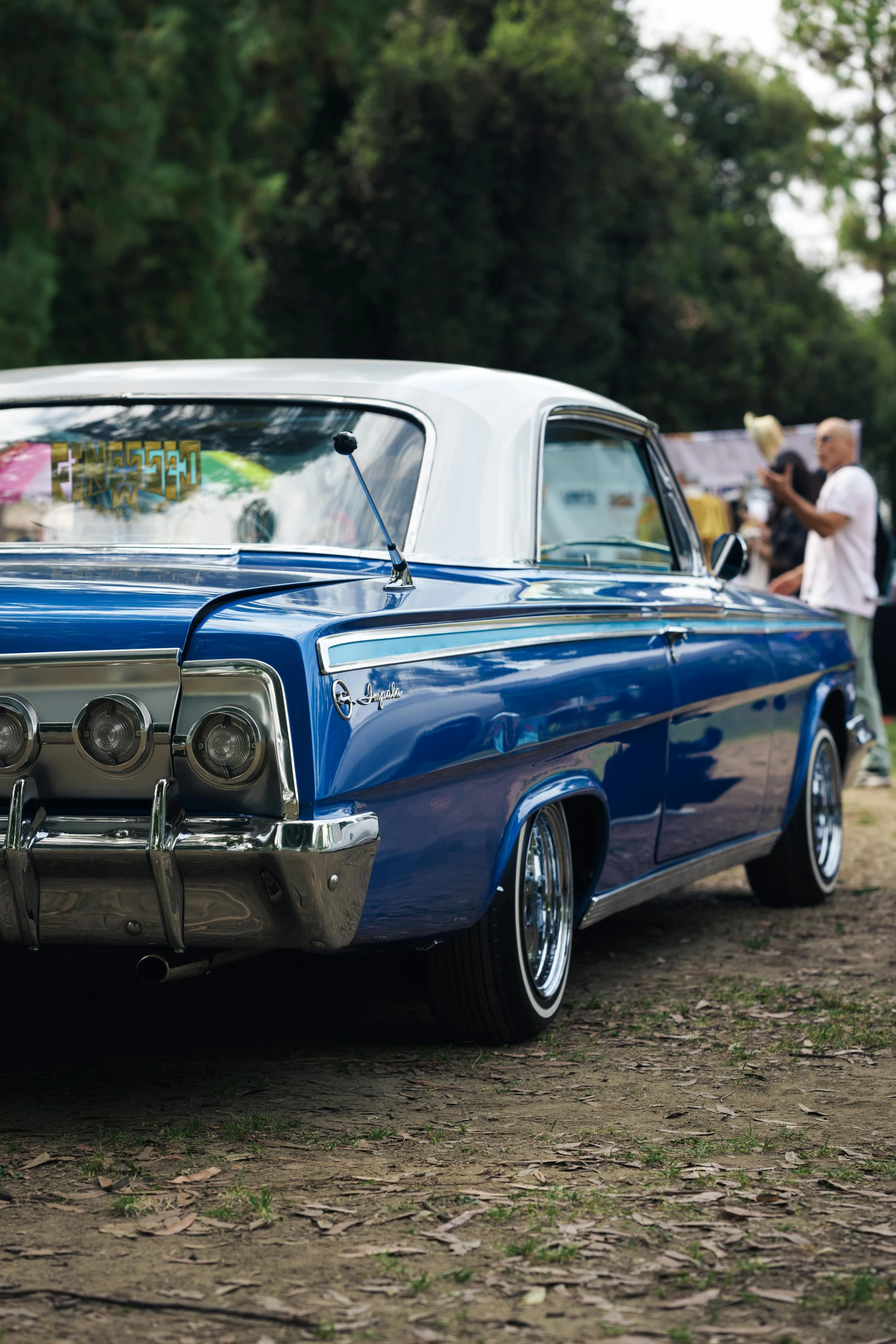 an old blue car parked on top of a dirt field