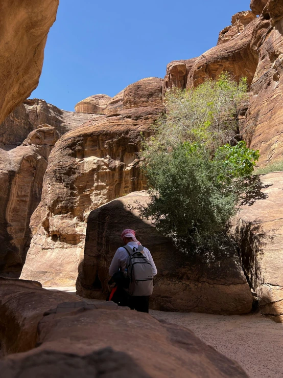 person in jacket and backpack in front of a rocky area