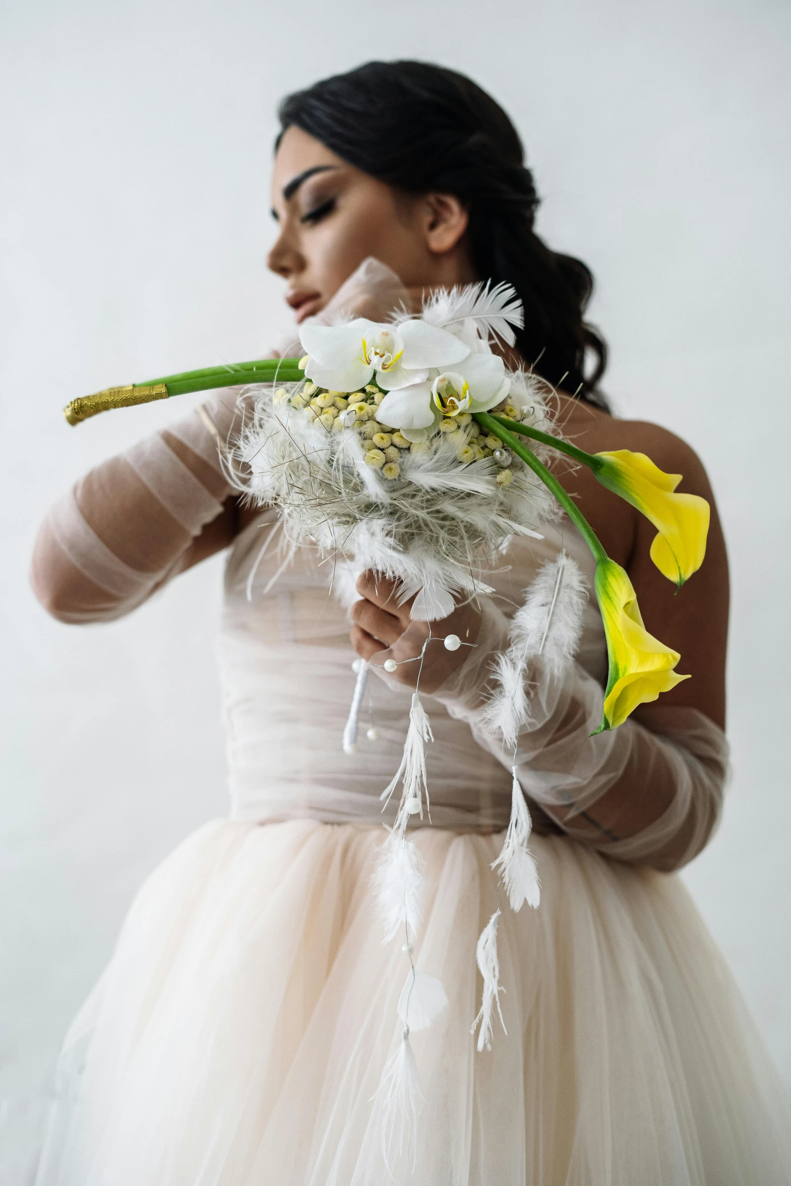 a woman with flower and feather bouquet in a dress