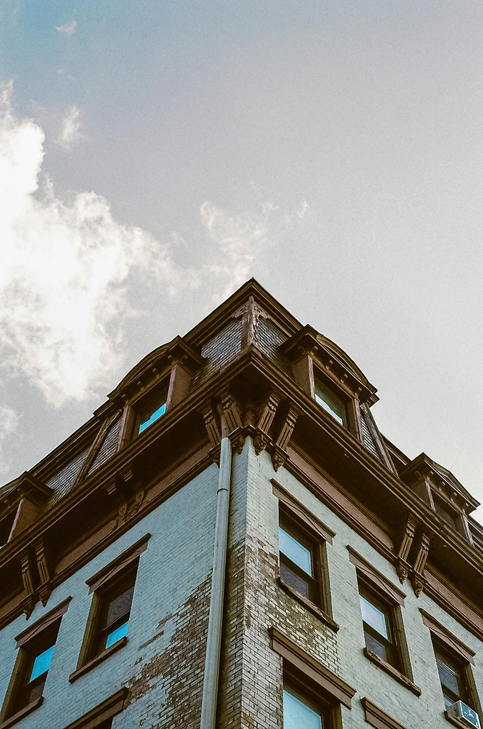 a blue building with multiple windows in front of a cloudy sky