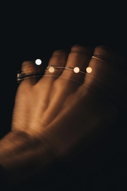 a hand with gold chain and tiny lights