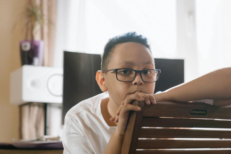 a man sits on a bench with his hand on his chin