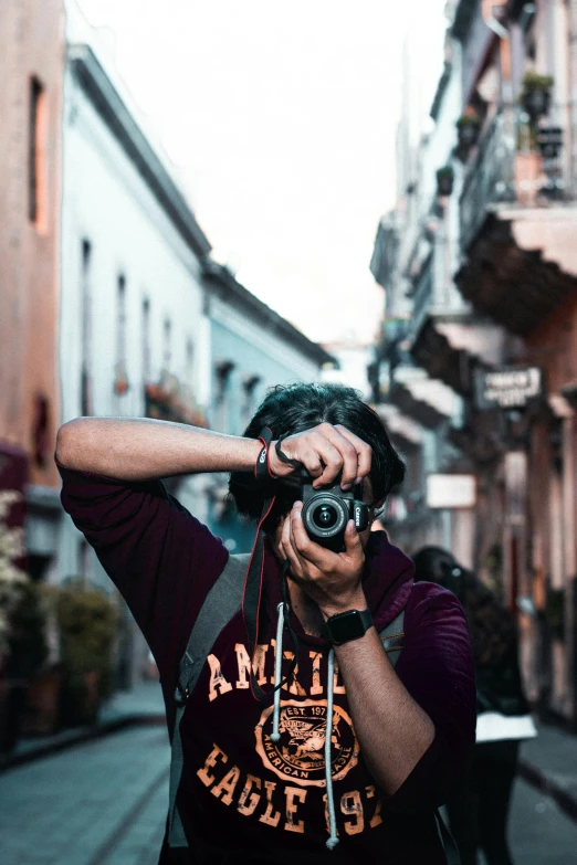 a man standing in the middle of a street holding up a camera