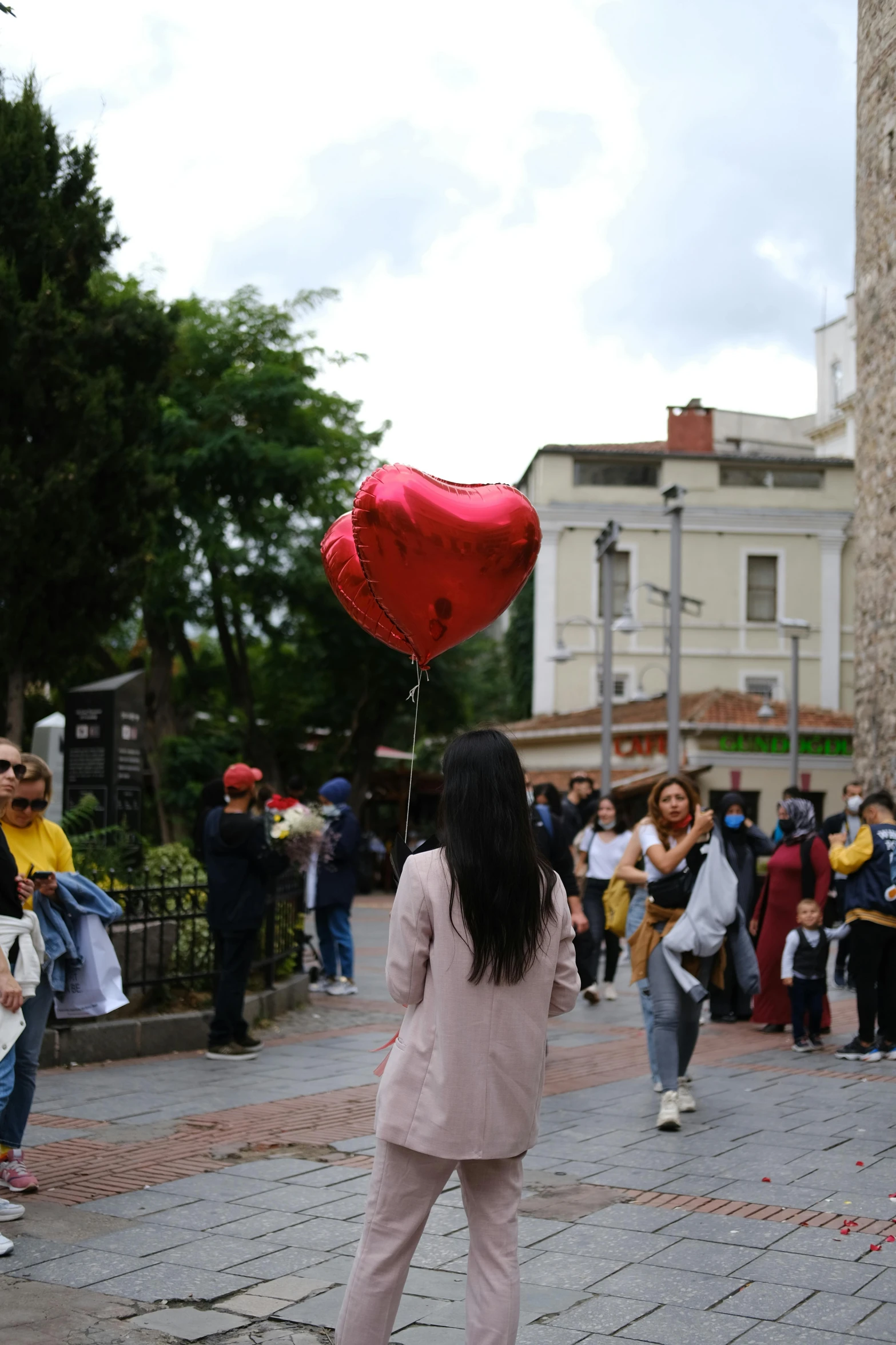 a woman walking with a red heart balloon in hand