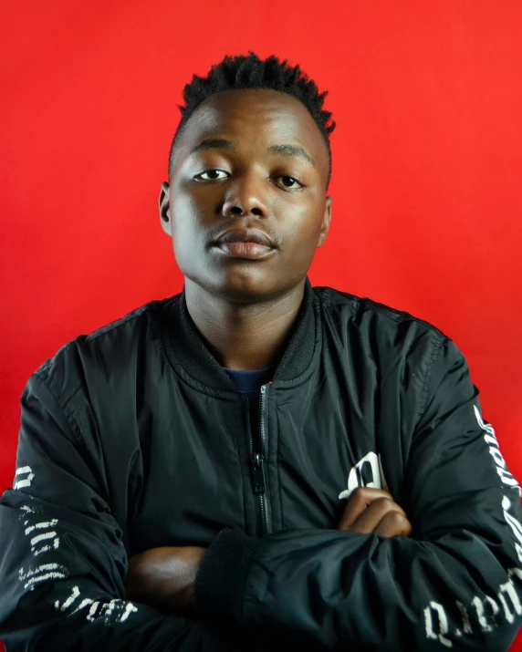 a young man posing in front of a red background