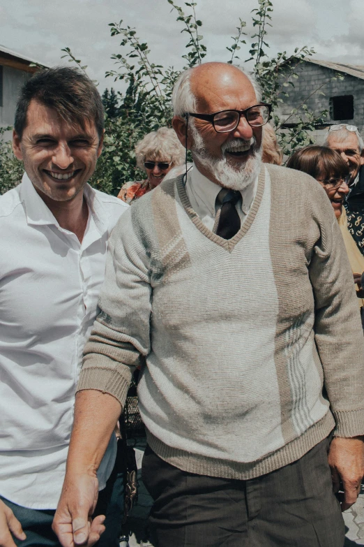 two older gentlemen are walking while people stand around