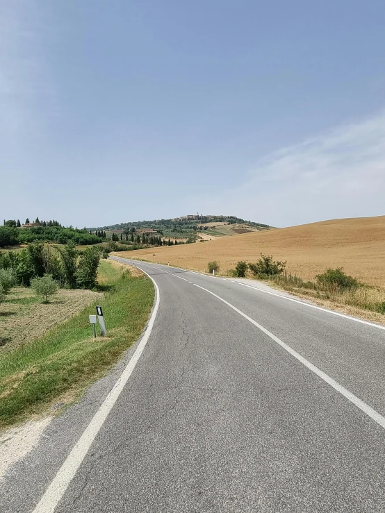 the road is paved and there are hills on either side