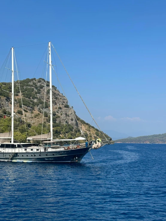 a boat sailing on the water near a hill