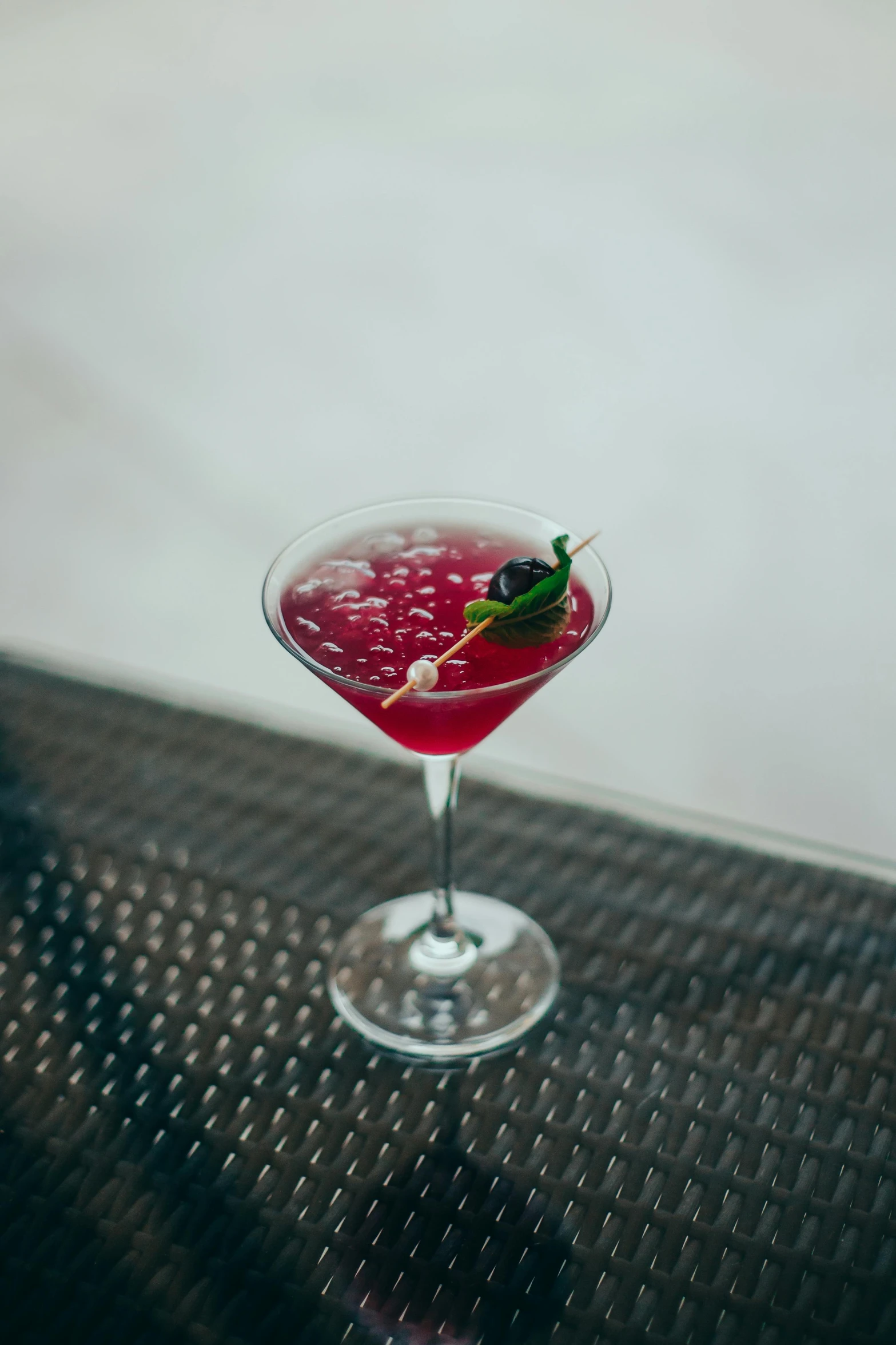 a martini glass filled with red liquid and topped with a lime