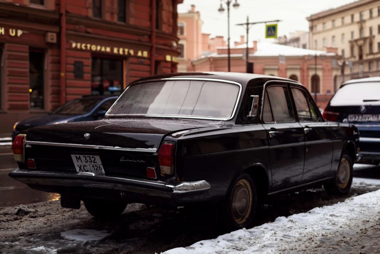 old car parked on the side of a snowy street