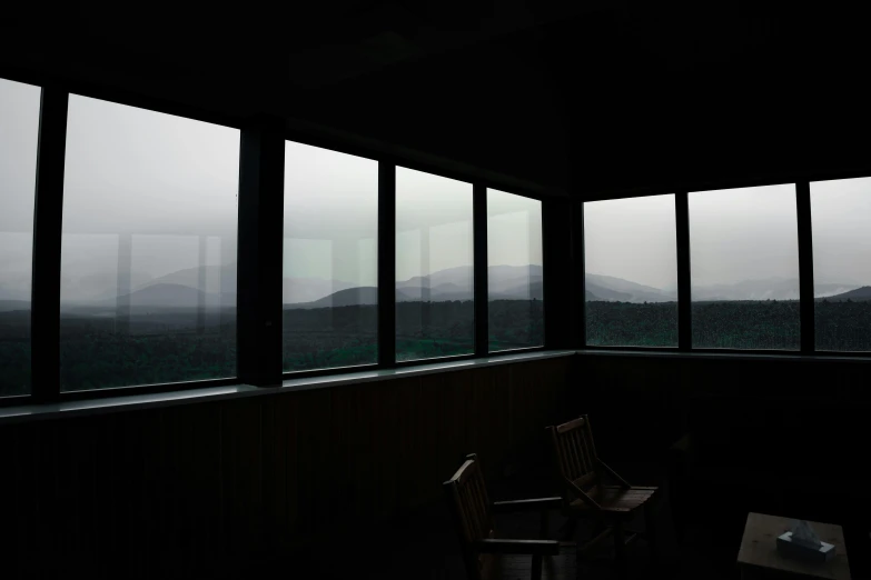 a lone chair sitting in an empty room by big windows