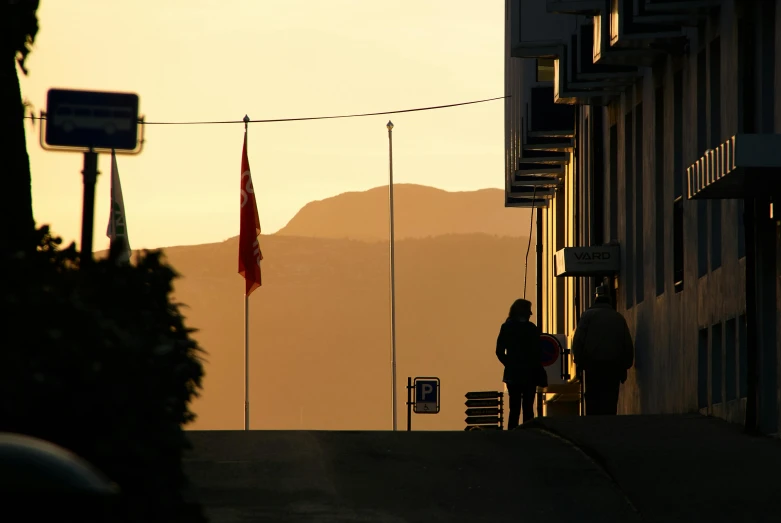 two people are walking down the street in front of some flags