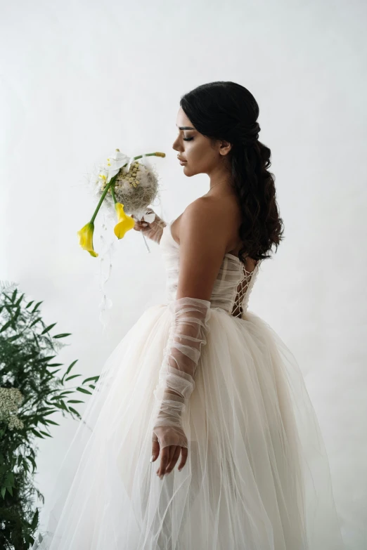 there is a woman dressed in an off white dress holding flowers