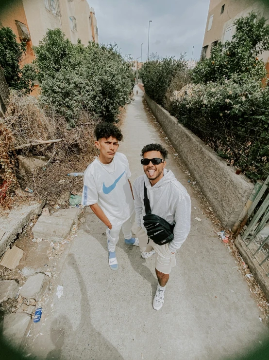 two men walking down an alley way with trees in the background