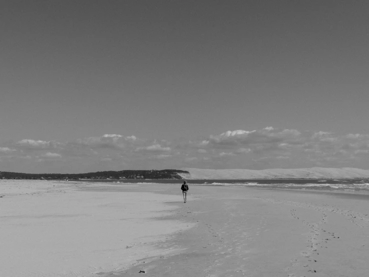 a person walks across the sand near a body of water