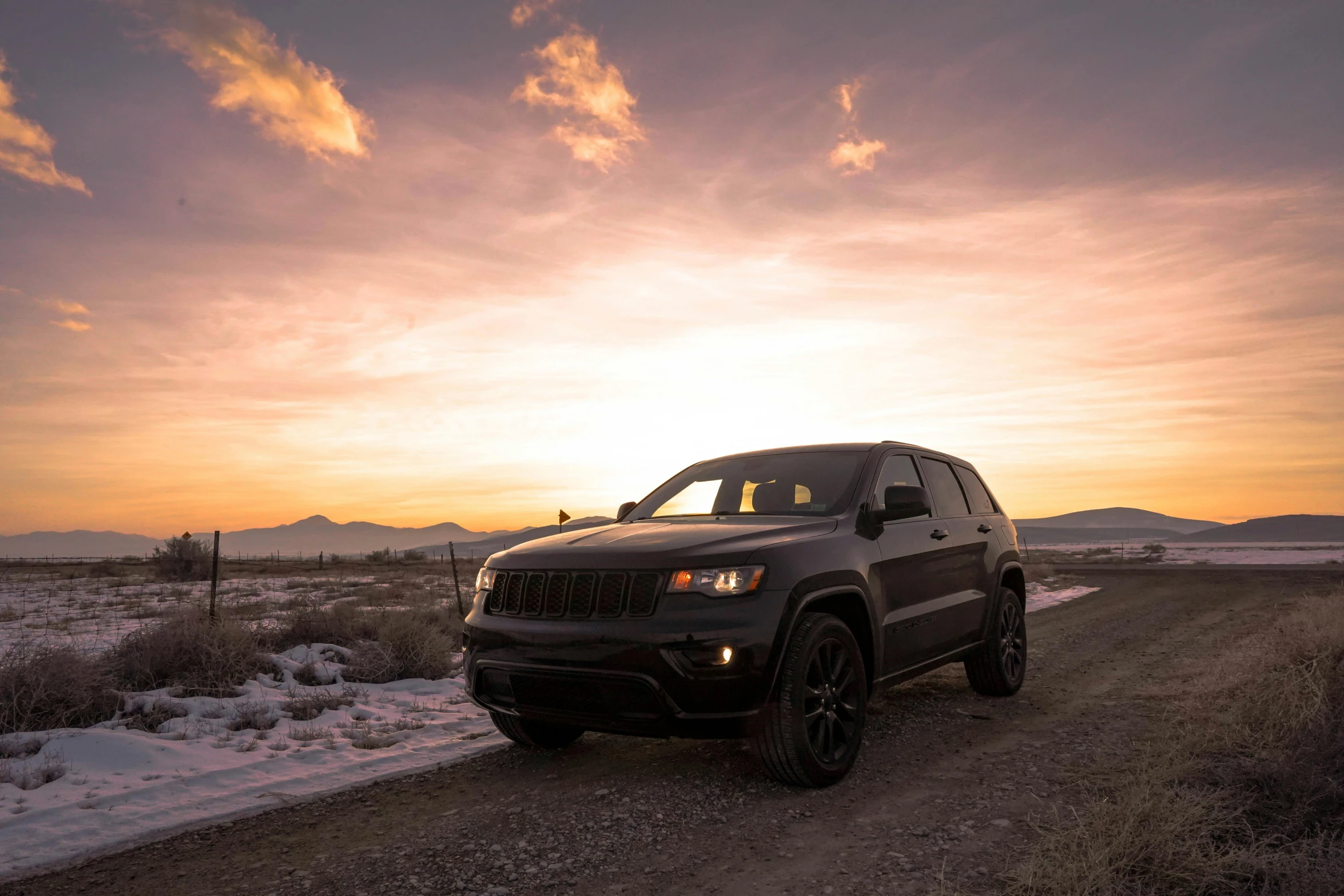 the suv is parked near the dirt road