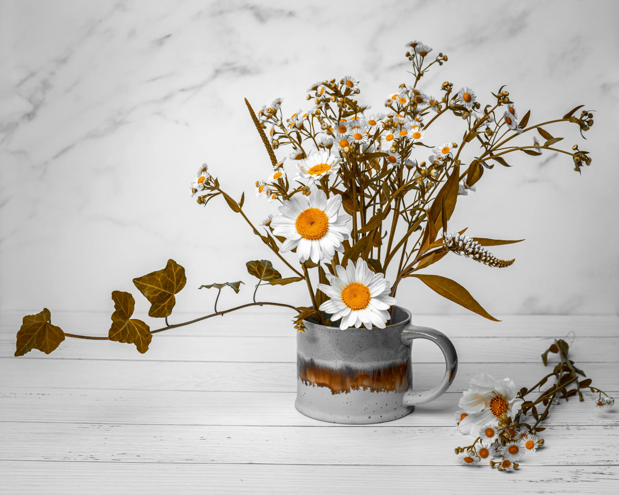 a white and orange vase of flowers next to a marble background