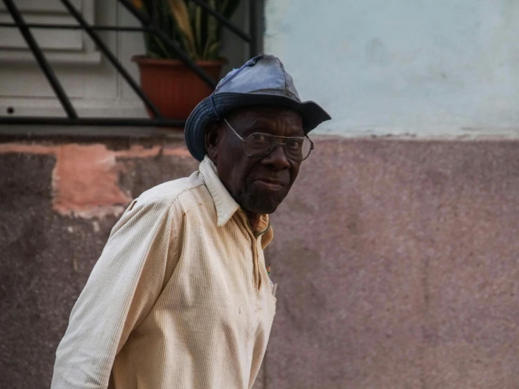 an old man in glasses and a hat is on the street