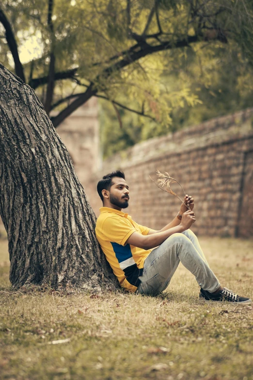 a man sits on the grass holding a stick