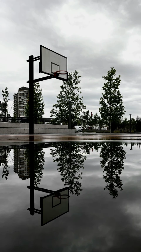 the reflection of two basketball hoops and buildings in a body of water