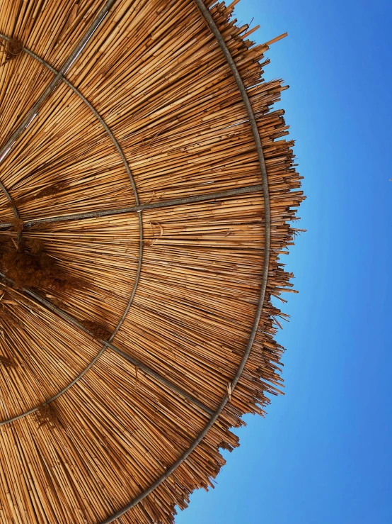 a tan umbrella in the sun that is opened to reveal clear blue skies