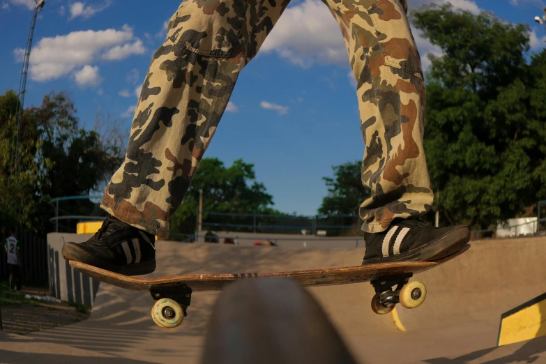 a person in camo pants is doing a skateboard trick