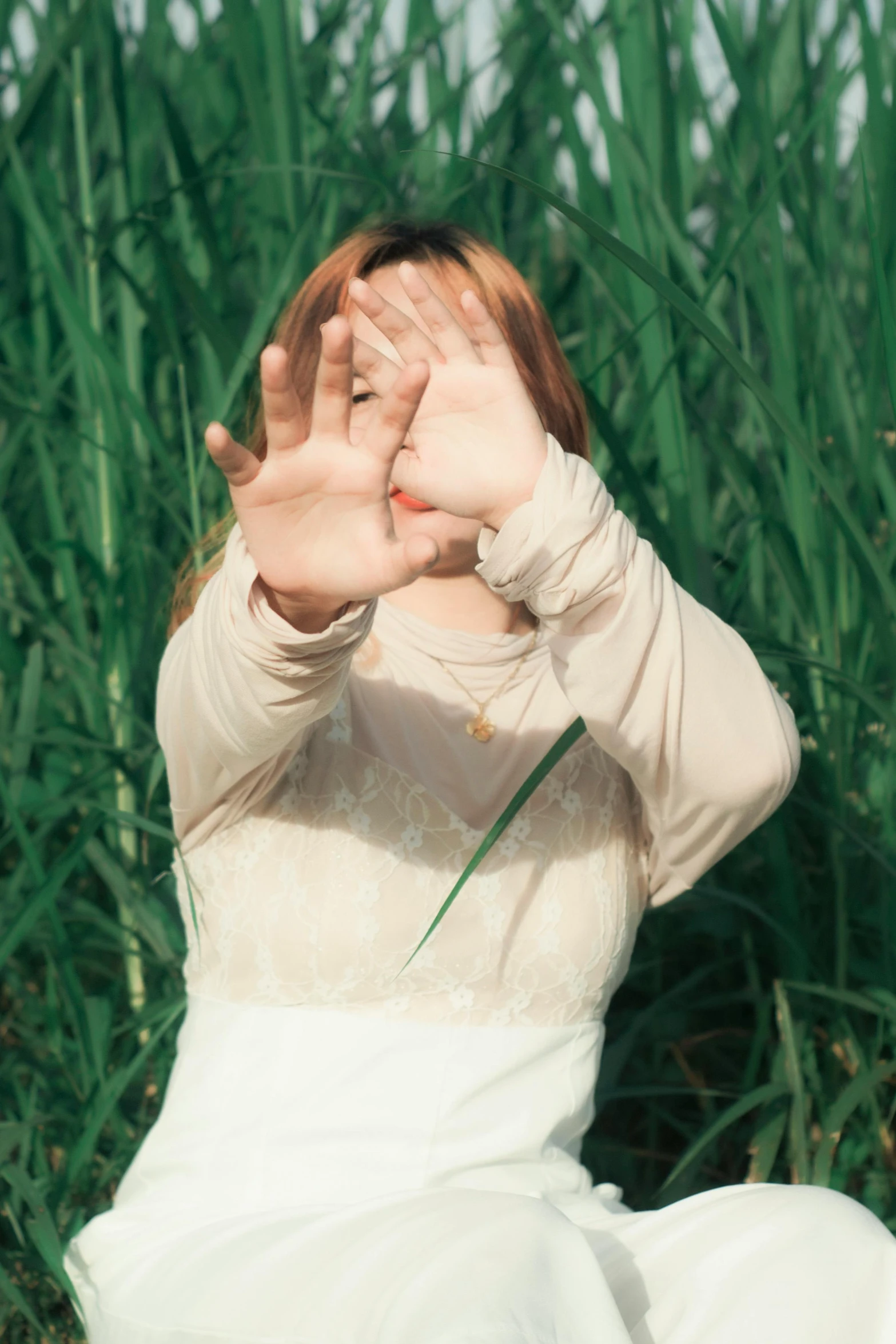 a woman wearing a white dress is covering her face with her hands