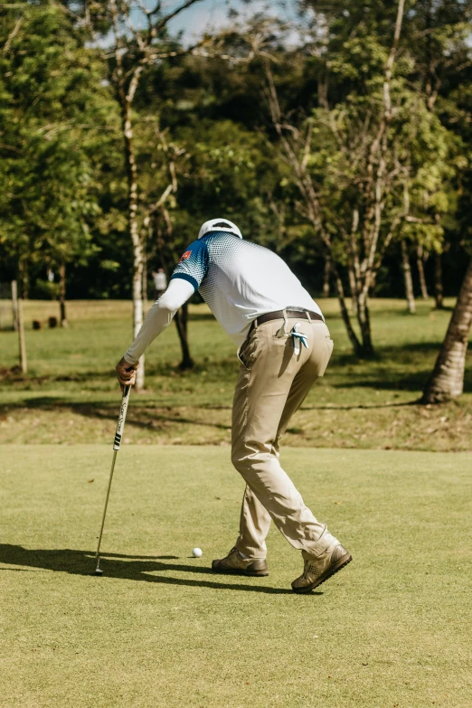 man about to put a ball in his golf putter's green