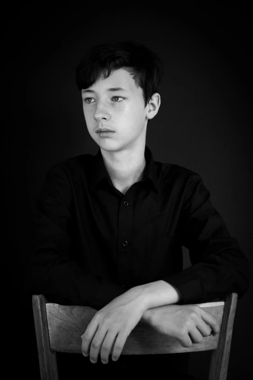 a young man sits in a chair looking straight ahead