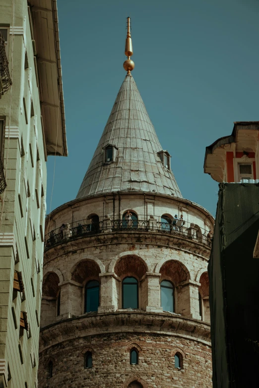 a tall round building with a tower next to other buildings