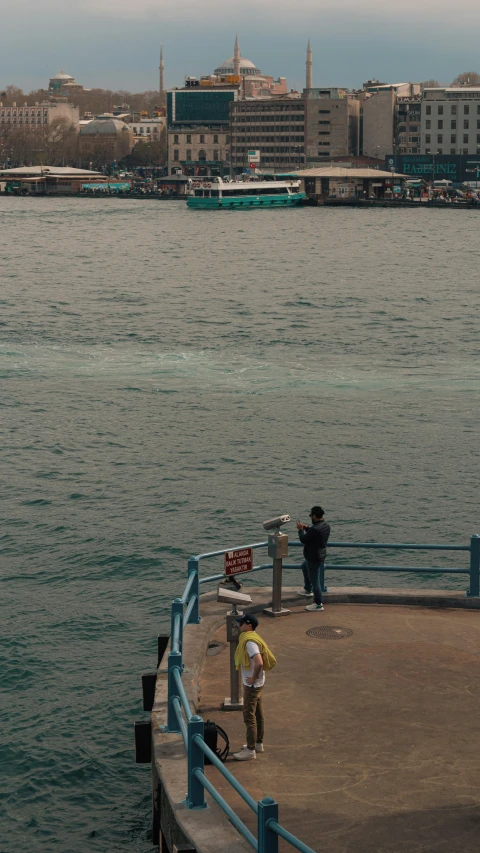 people are standing near the ocean with umbrellas